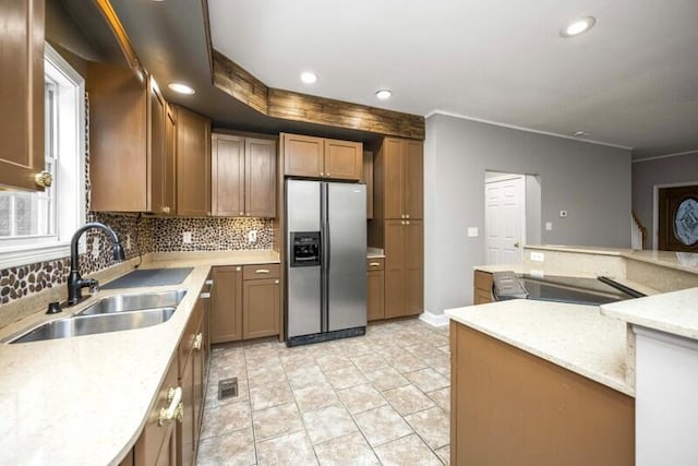 kitchen with recessed lighting, a sink, backsplash, brown cabinets, and stainless steel fridge