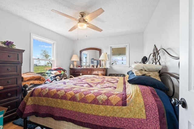 bedroom with ceiling fan, a textured ceiling, and wood finished floors