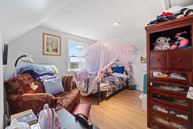 bedroom featuring a textured ceiling, vaulted ceiling, and wood finished floors