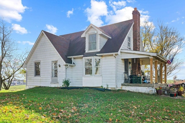 view of front facade with covered porch, a shingled roof, a chimney, and a front lawn