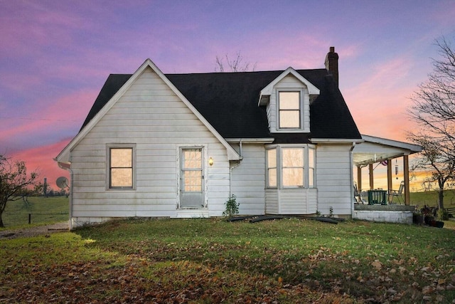 view of front facade featuring covered porch, a chimney, and a yard