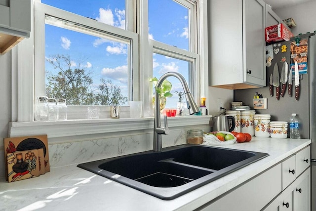 kitchen featuring light countertops, a sink, and white cabinetry