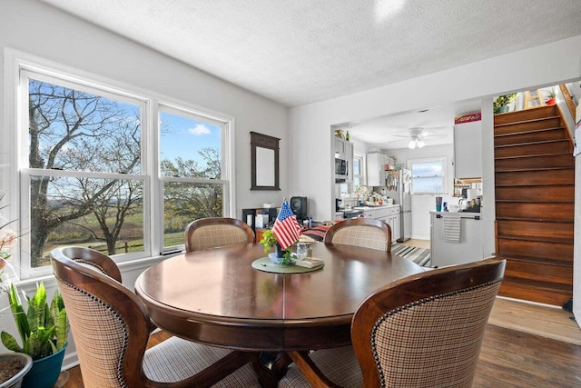 dining area with a textured ceiling, stairway, wood finished floors, and a ceiling fan