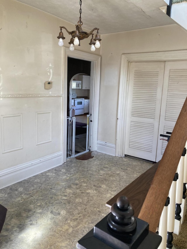 kitchen with arched walkways, white appliances, and a notable chandelier