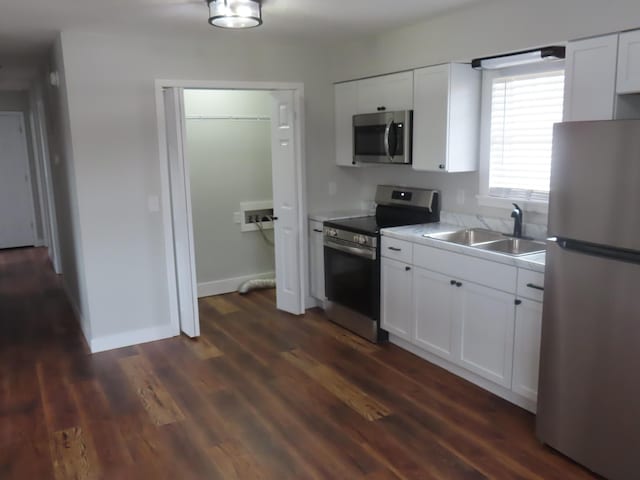 kitchen with stainless steel appliances, white cabinetry, a sink, and dark wood-style floors