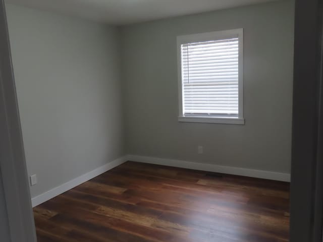 empty room with dark wood finished floors and baseboards