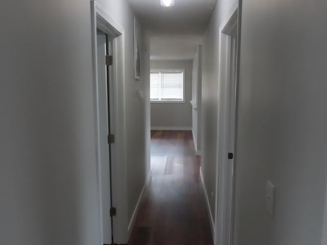 corridor with dark wood finished floors and baseboards