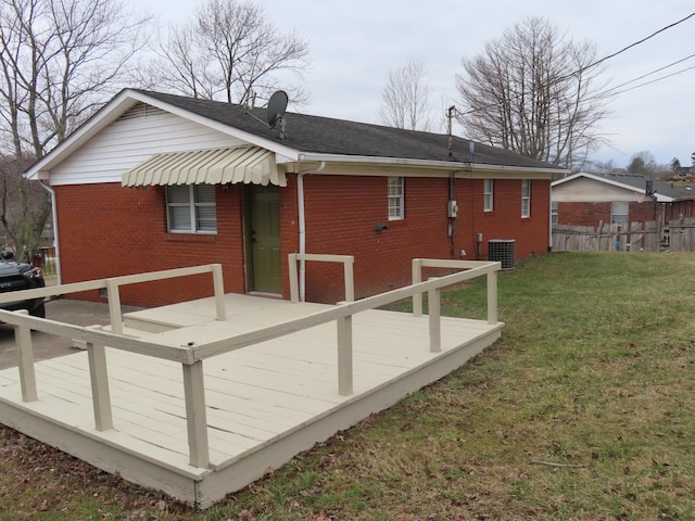 rear view of property featuring a yard, fence, a deck, and brick siding