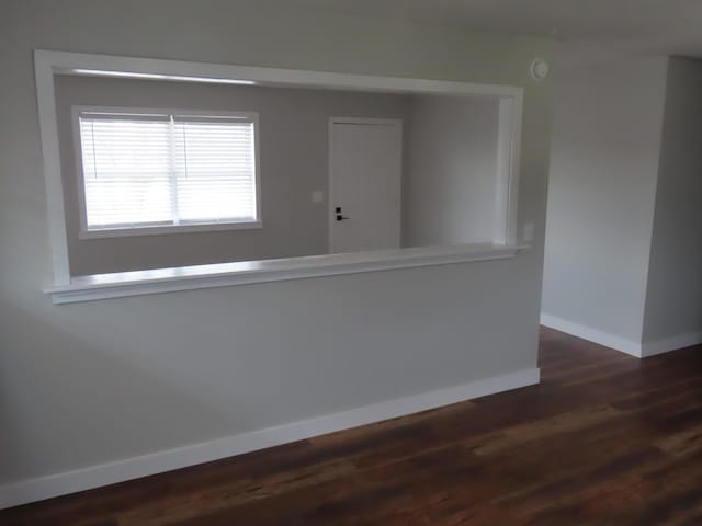 spare room with dark wood-style flooring and baseboards