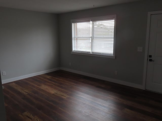 spare room featuring dark wood-style floors and baseboards