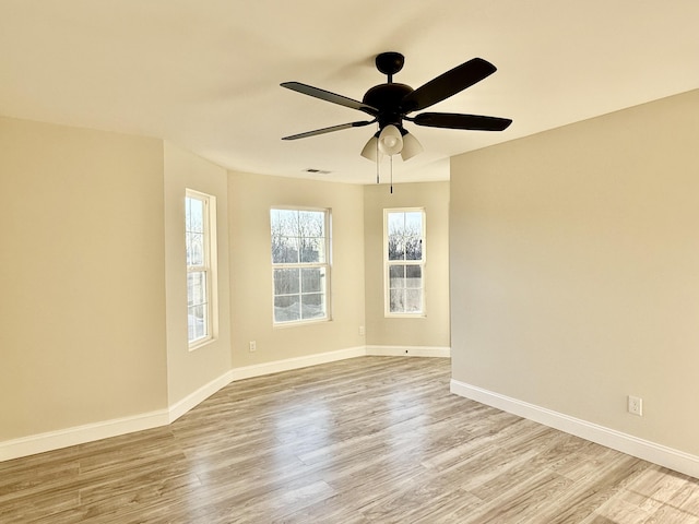 spare room featuring visible vents, a ceiling fan, light wood-type flooring, and baseboards