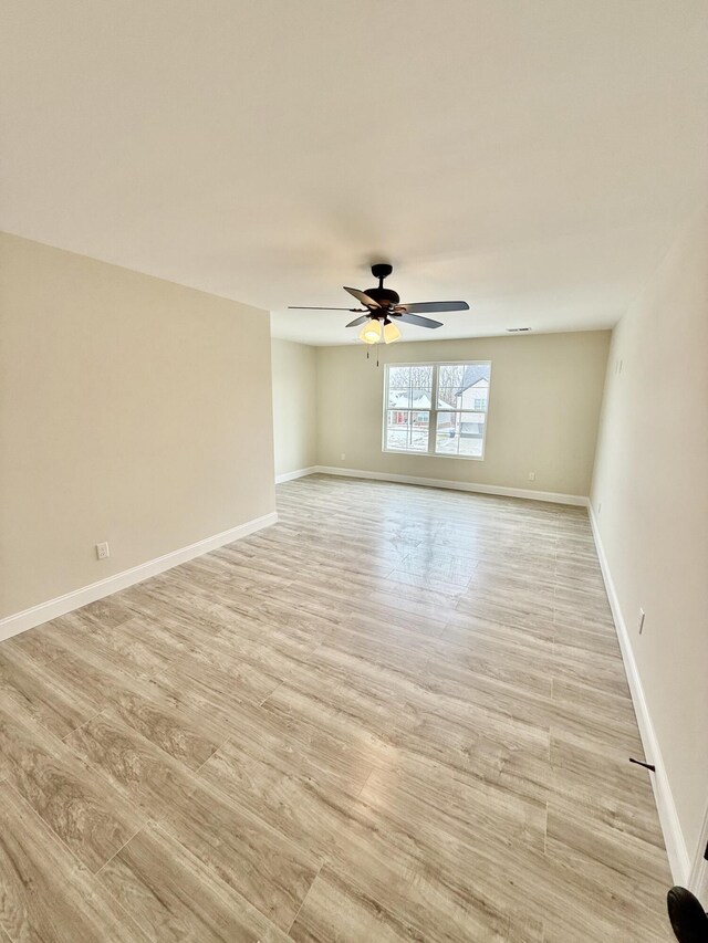 unfurnished room with a ceiling fan, light wood-style floors, and baseboards