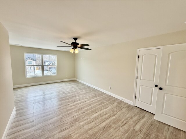 unfurnished room with baseboards, light wood-style floors, and a ceiling fan