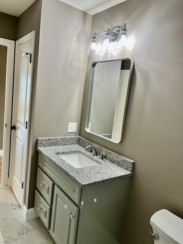 bathroom featuring vanity, toilet, baseboards, and marble finish floor