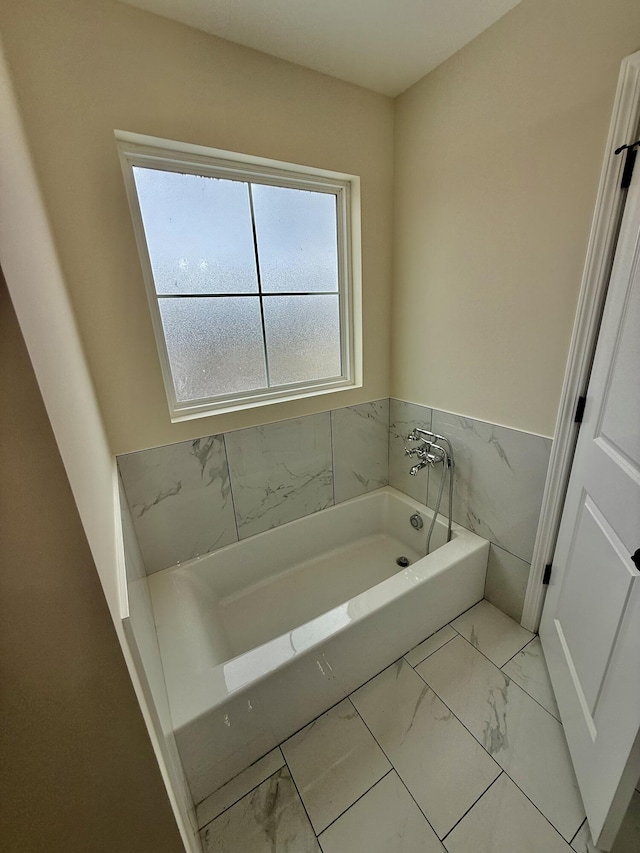 full bathroom with a bath and marble finish floor