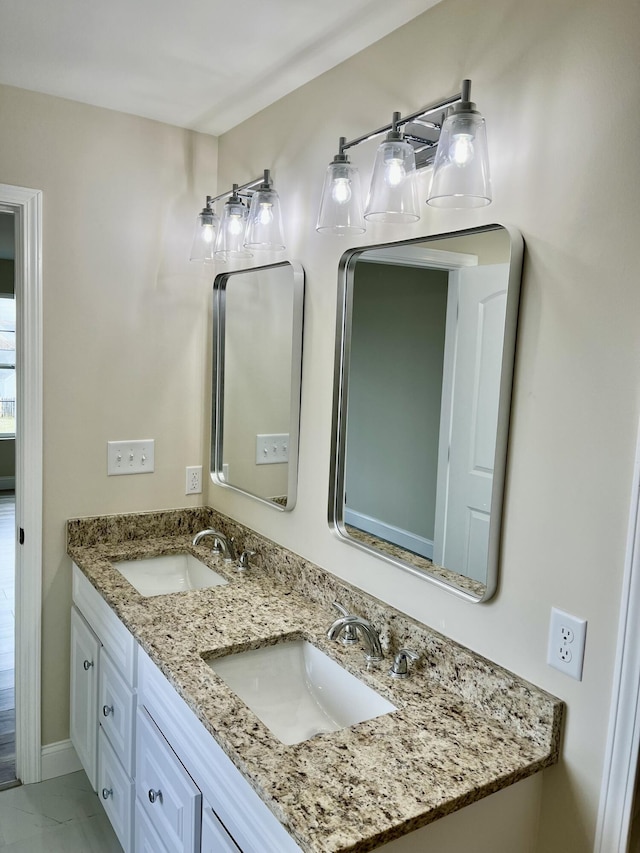 bathroom featuring double vanity, baseboards, and a sink