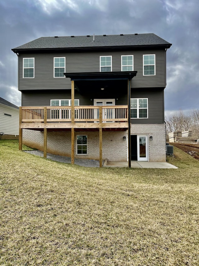 rear view of property with a deck, a patio, a yard, and central AC