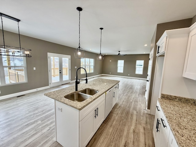 kitchen with a center island with sink, white dishwasher, a sink, light wood-style floors, and open floor plan