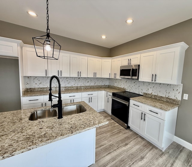 kitchen featuring stainless steel microwave, white cabinets, electric range oven, and a sink