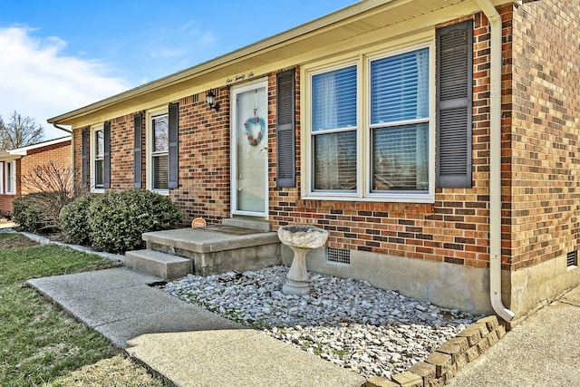 view of exterior entry featuring crawl space and brick siding