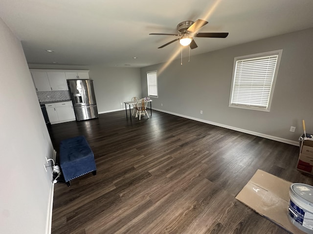 unfurnished living room with baseboards, dark wood finished floors, and a ceiling fan