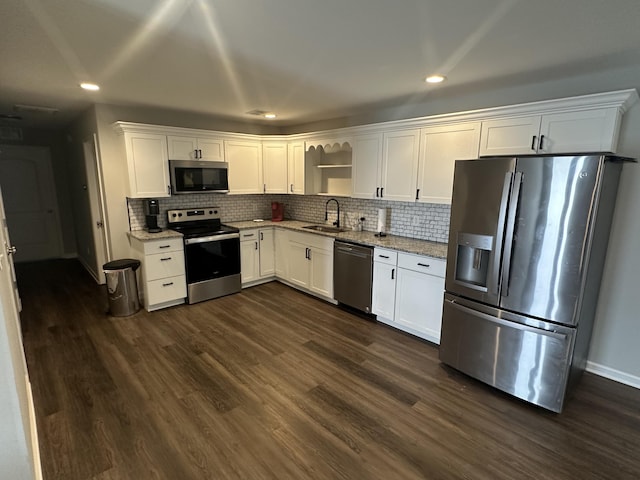 kitchen with appliances with stainless steel finishes, dark wood-type flooring, a sink, and white cabinetry