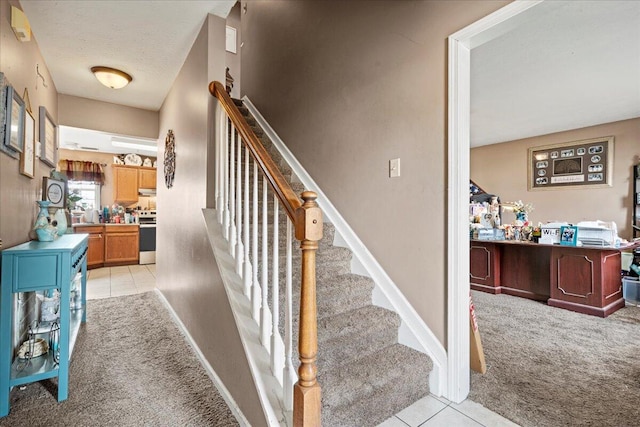 stairs with tile patterned floors, a textured ceiling, baseboards, and carpet