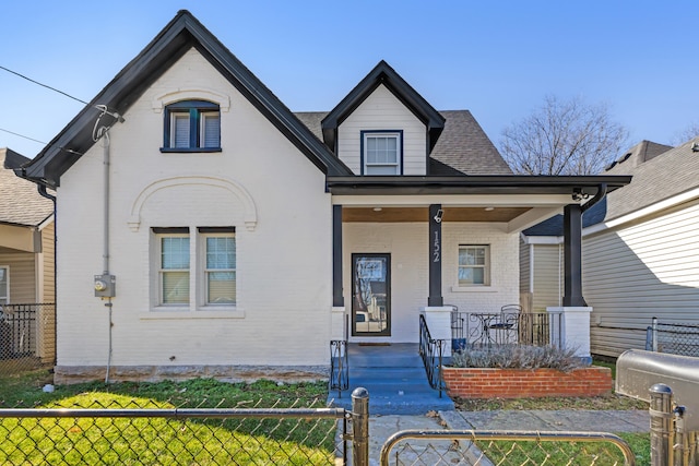 view of front of home with a fenced front yard, covered porch, and brick siding