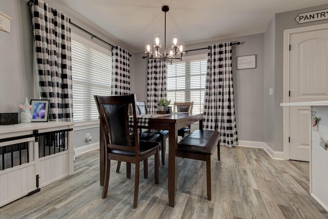 dining space featuring a chandelier, baseboards, and light wood-style floors