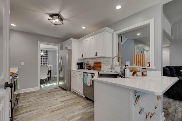 kitchen featuring backsplash, light wood-style floors, white cabinets, stainless steel appliances, and a sink