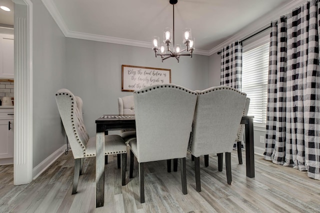 dining area featuring light wood finished floors, a notable chandelier, baseboards, and ornamental molding