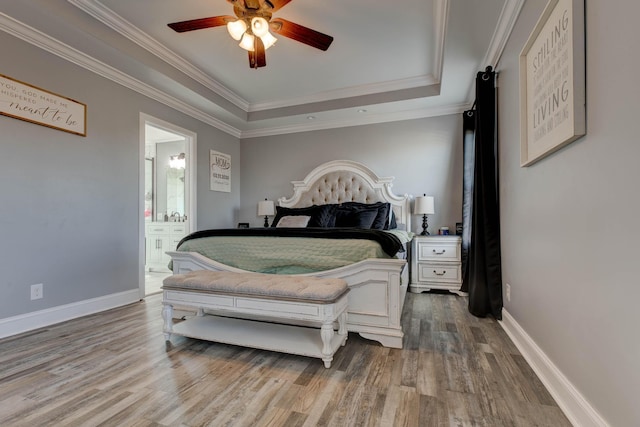 bedroom featuring a tray ceiling, baseboards, wood finished floors, and crown molding