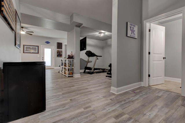 workout area featuring light wood finished floors, a ceiling fan, and baseboards