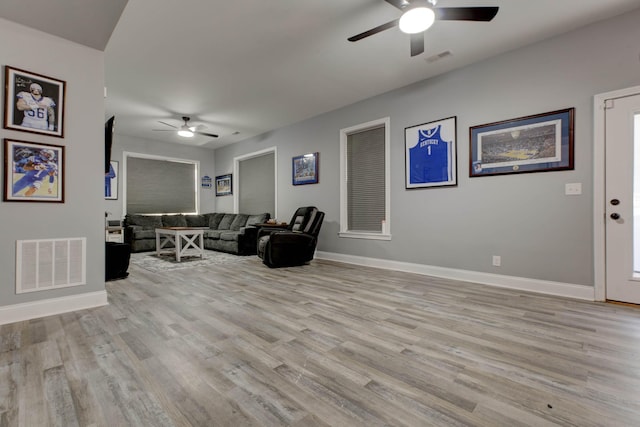 living room with ceiling fan, visible vents, baseboards, and light wood-style flooring