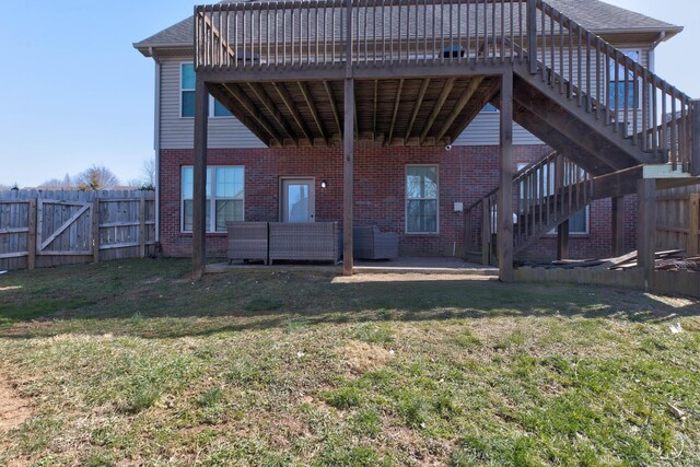 rear view of property featuring brick siding, fence, stairway, a yard, and a patio area