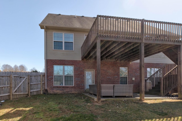 back of property featuring stairway, fence, a wooden deck, a yard, and brick siding