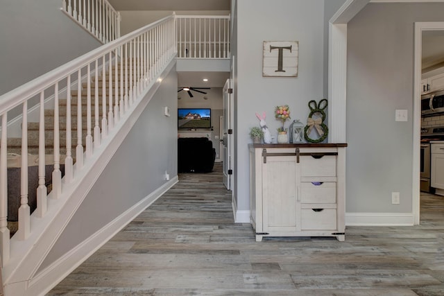 stairs with a ceiling fan, wood finished floors, and baseboards