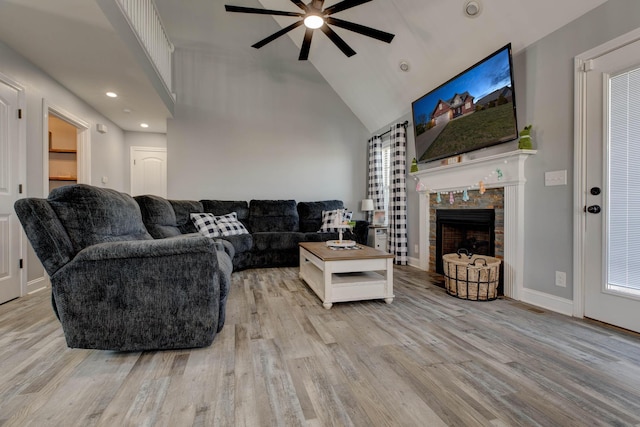 living room with wood finished floors, baseboards, high vaulted ceiling, ceiling fan, and a tile fireplace