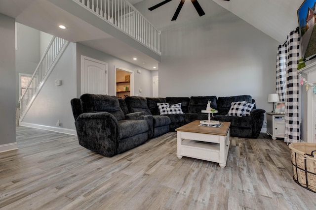 living area featuring a towering ceiling, baseboards, wood finished floors, and stairs