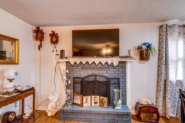 interior details with a textured ceiling, a fireplace, and wood finished floors