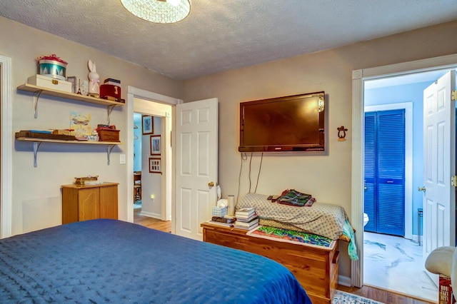 bedroom with a textured ceiling, baseboards, and wood finished floors