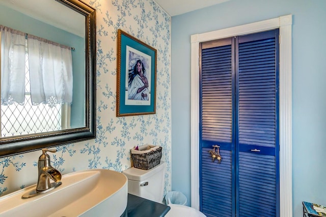 half bath with wallpapered walls, a wealth of natural light, and a sink