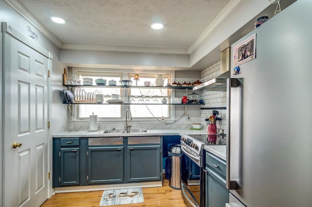 kitchen with electric stove, light countertops, ornamental molding, freestanding refrigerator, and a sink