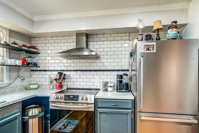 kitchen with tasteful backsplash, wall chimney exhaust hood, wood finished floors, blue cabinets, and stainless steel appliances