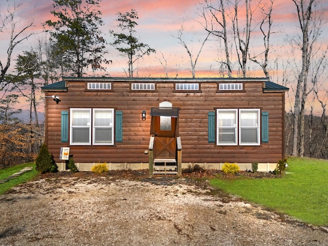 view of front of house with entry steps, log veneer siding, metal roof, and a front lawn