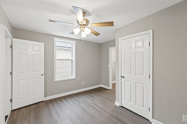 unfurnished bedroom with ceiling fan, baseboards, and wood finished floors