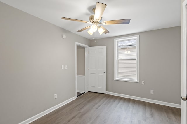 spare room with a ceiling fan, wood finished floors, and baseboards