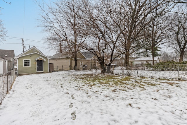 snowy yard with a detached garage and a fenced backyard