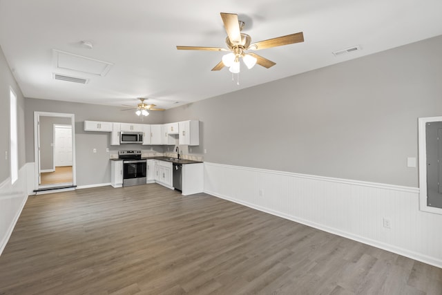 unfurnished living room featuring visible vents, dark wood-type flooring, a ceiling fan, and a wainscoted wall