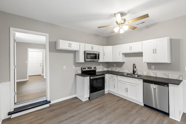 kitchen with dark countertops, visible vents, stainless steel appliances, white cabinetry, and a sink